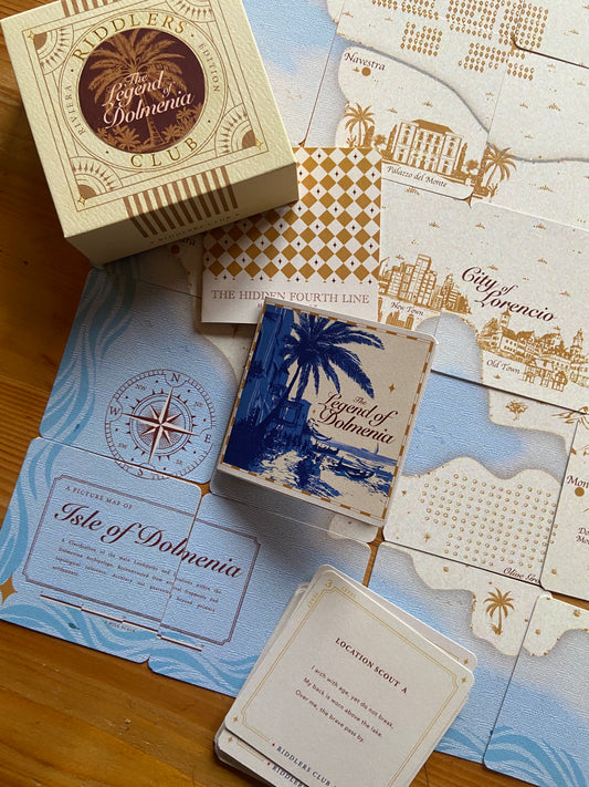 Collection of 'Legend of Dolmenia' cards and packaging on a wooden surface with map designs.