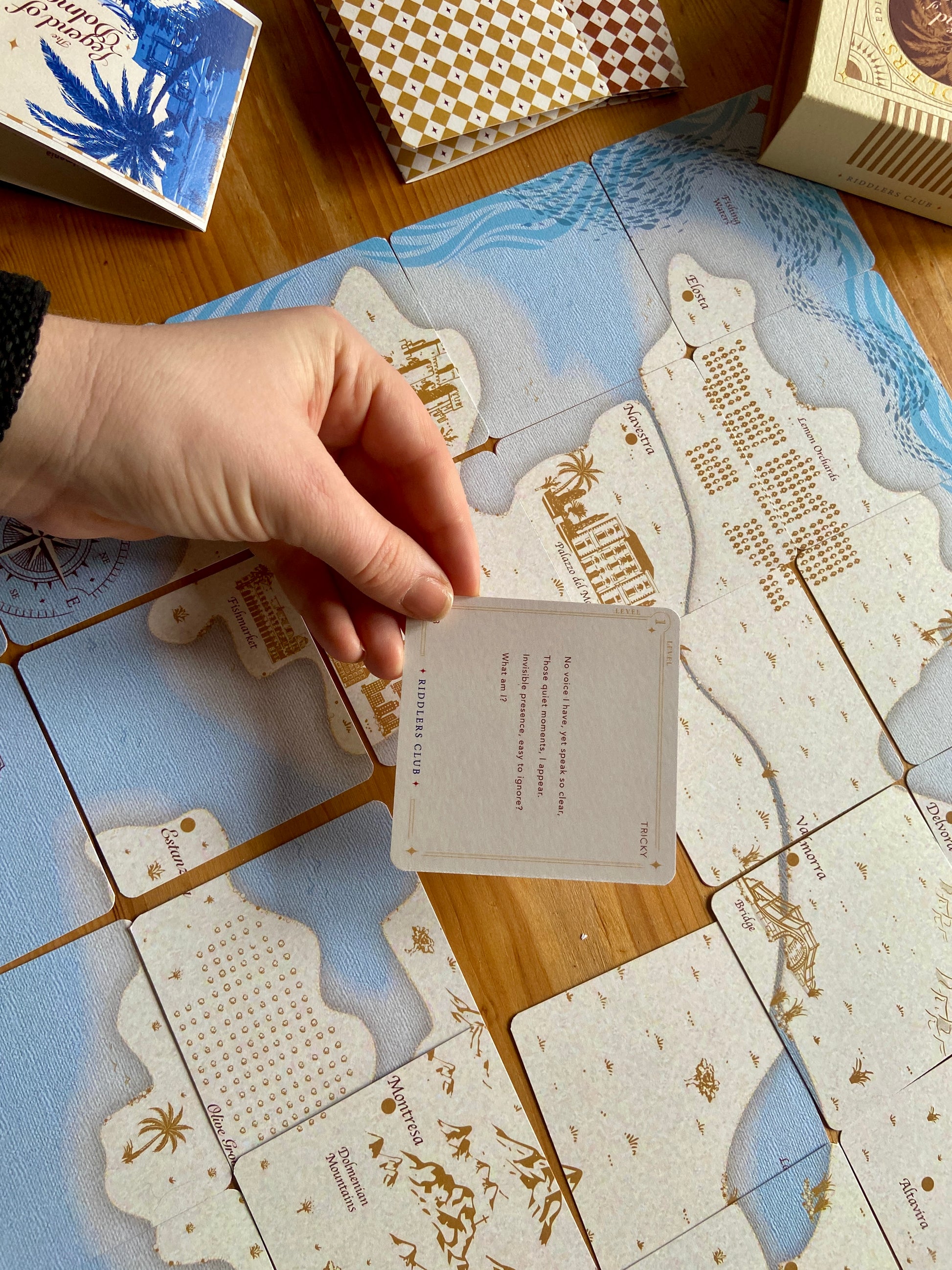 Hand holding a card over a decorative tile jigsaw surface with intricate designs 