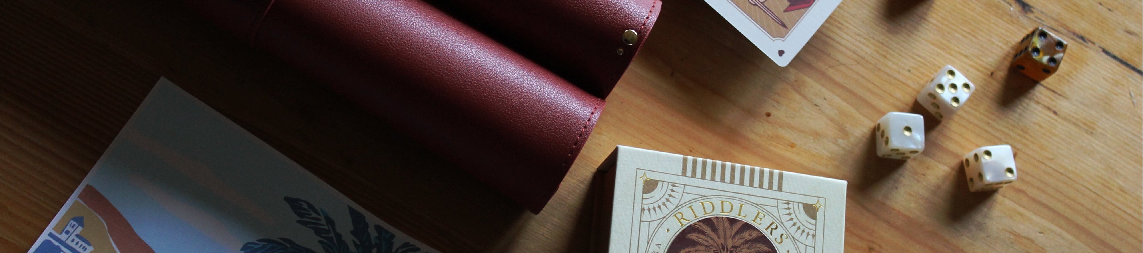 Playing cards, dice, and a leather-bound book on a wooden surface
